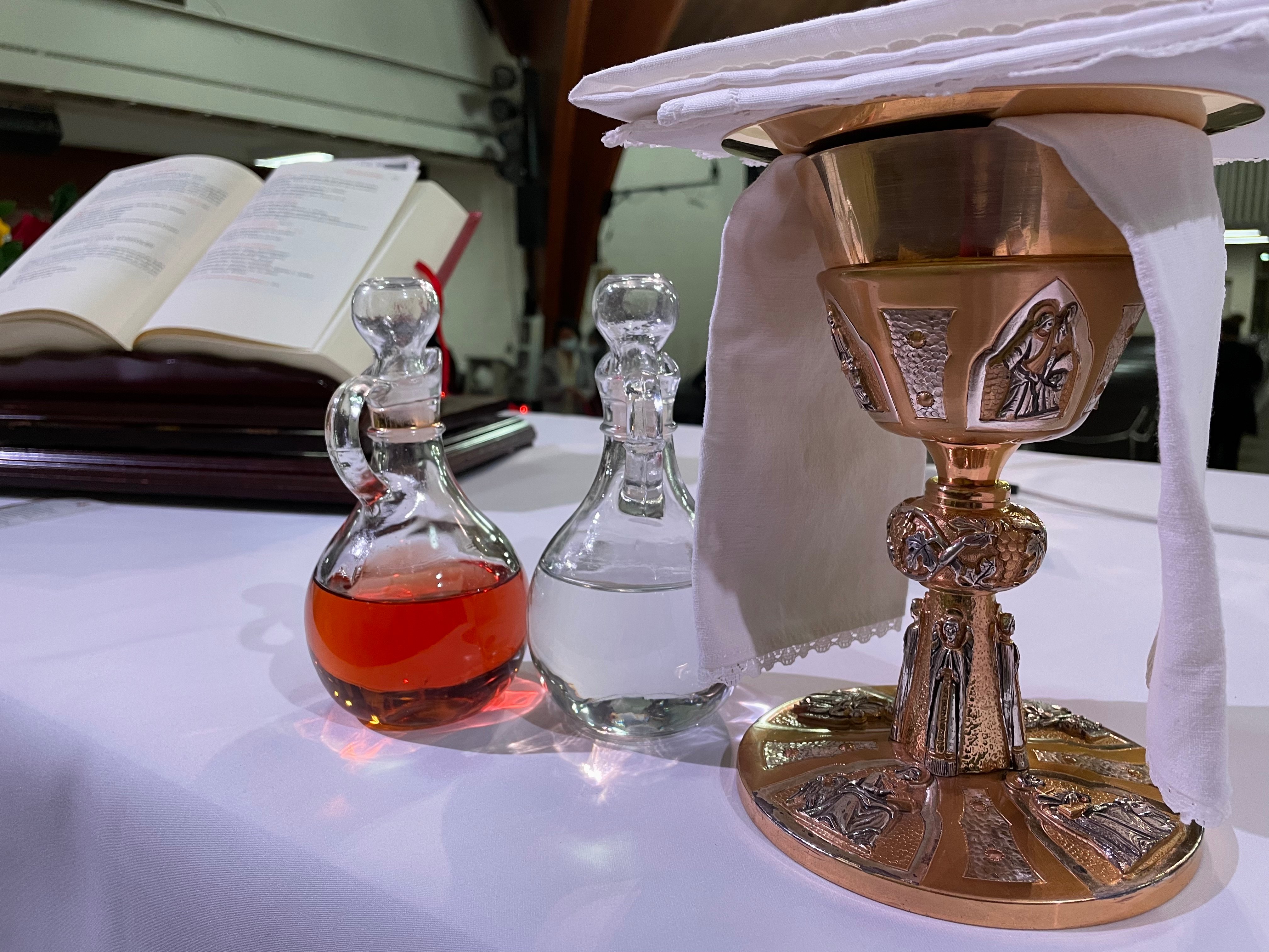 Side angle photo of a gold chalice and cruets (with water and wine in them) on the altar.