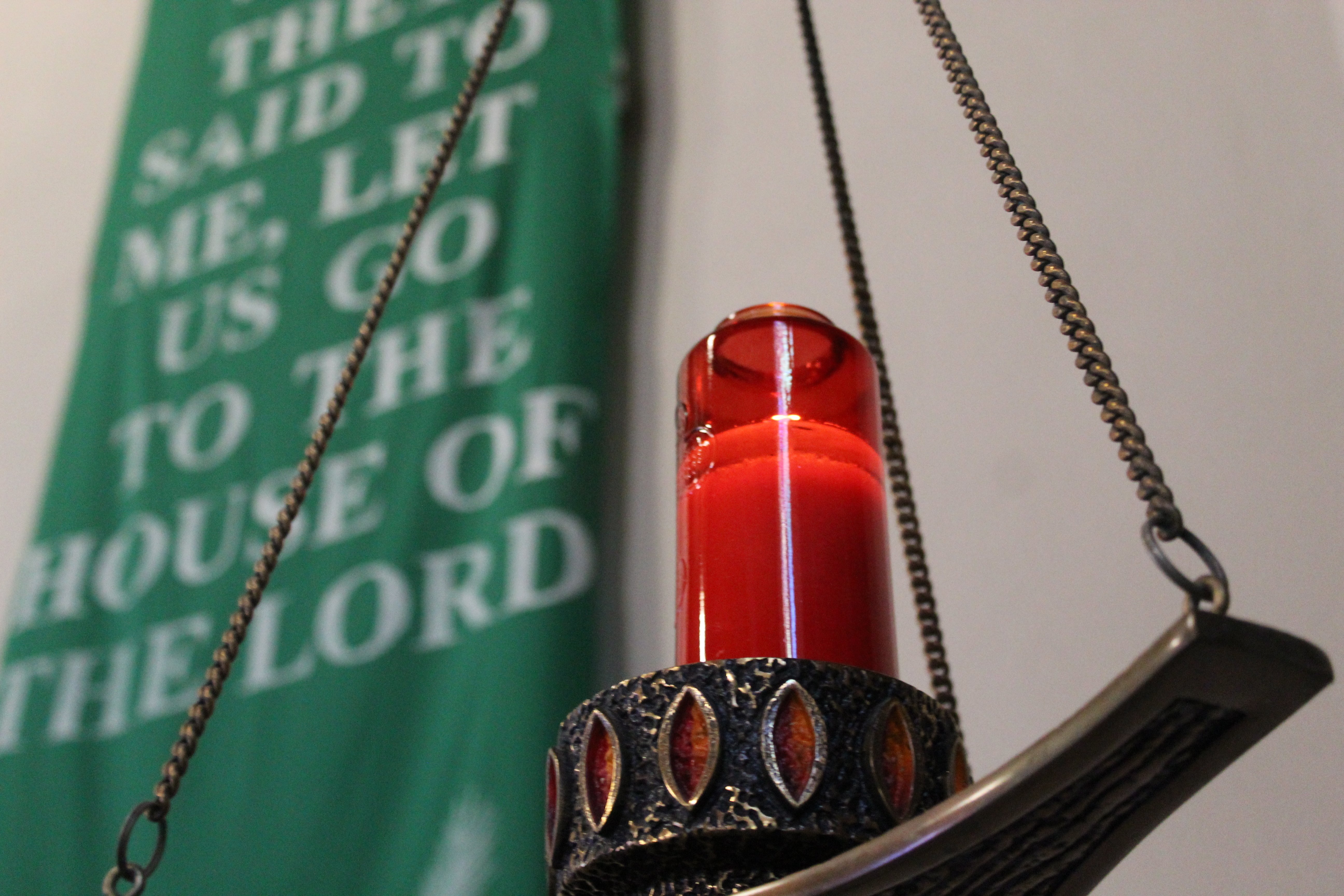 Tabernacle Red Candle lite with a green banner in the background.